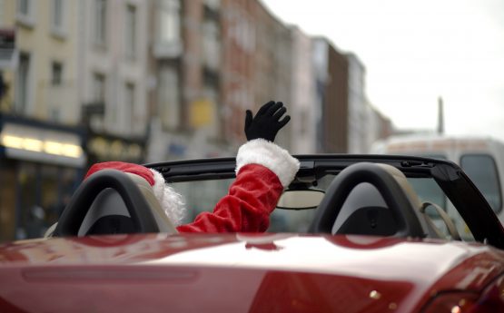 Santa Claus waving from a convertible