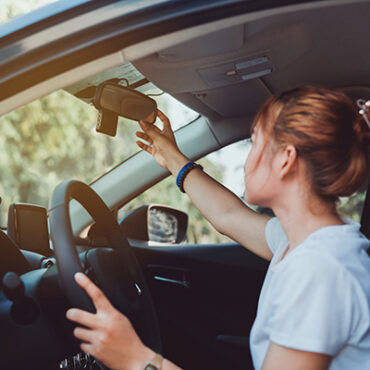 Woman adjusting car mirror