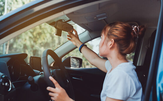 Woman adjusting car mirror
